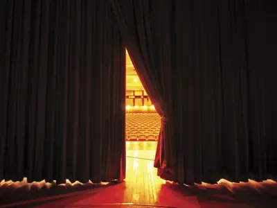 Stage curtain being drawn to reveal theatre